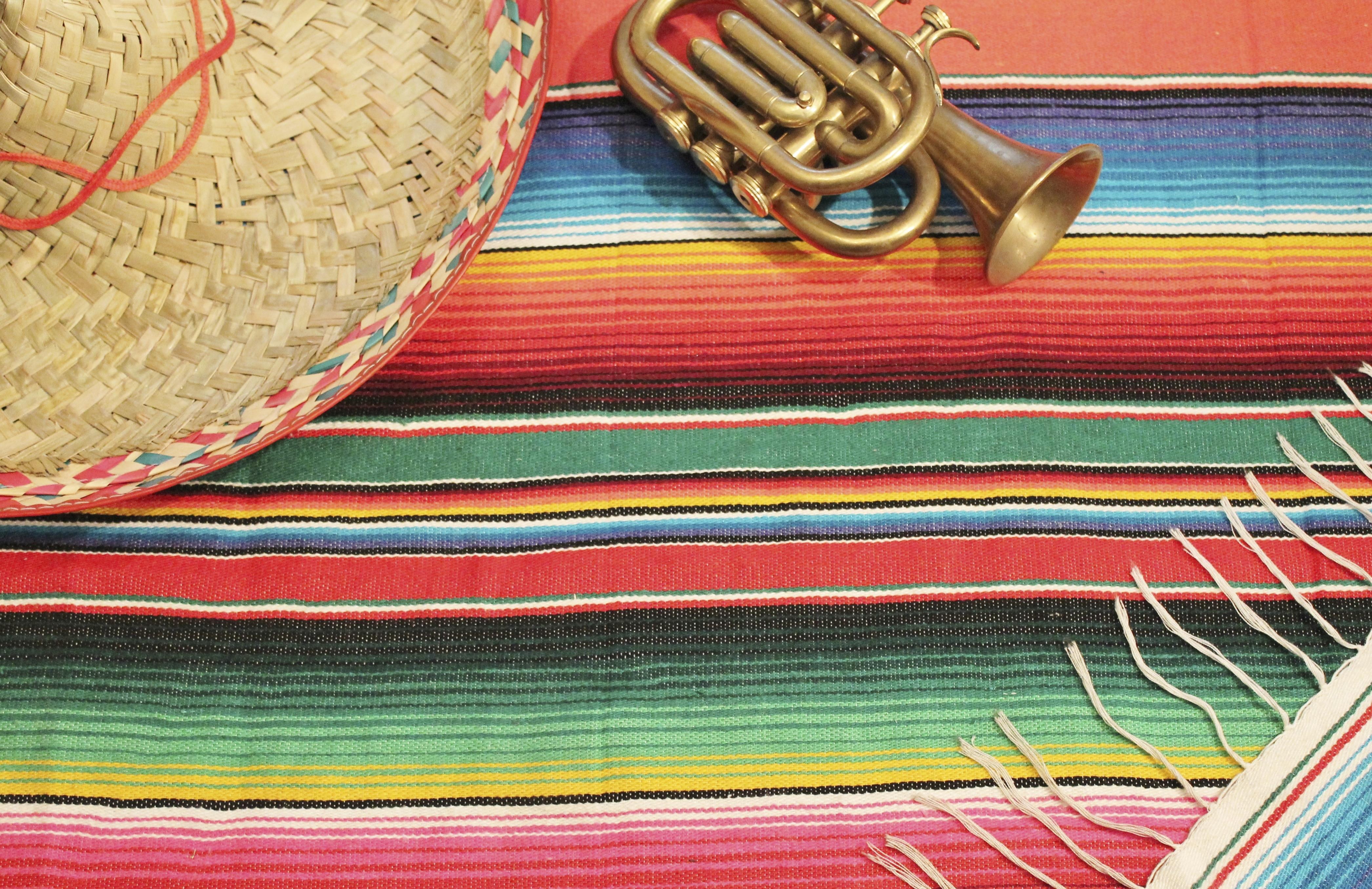 Traditional Mexican fiesta poncho rug in bright colors with sombrero background with copy space