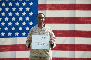 Black soldier holding I am strong sign near American flag