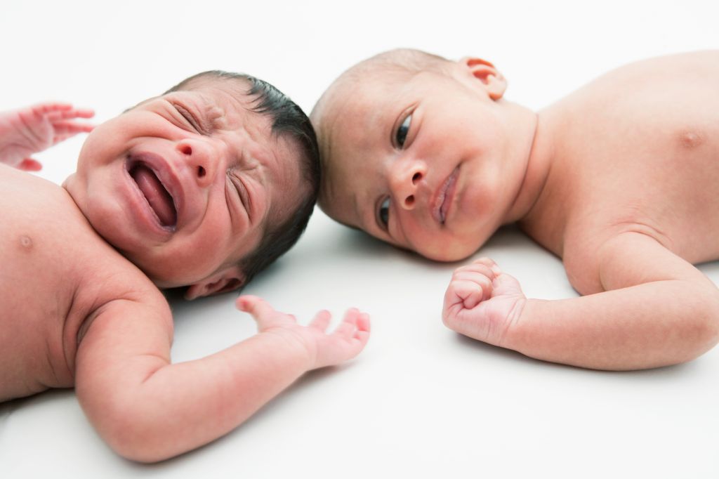 2 young babies lying down, 1 crying
