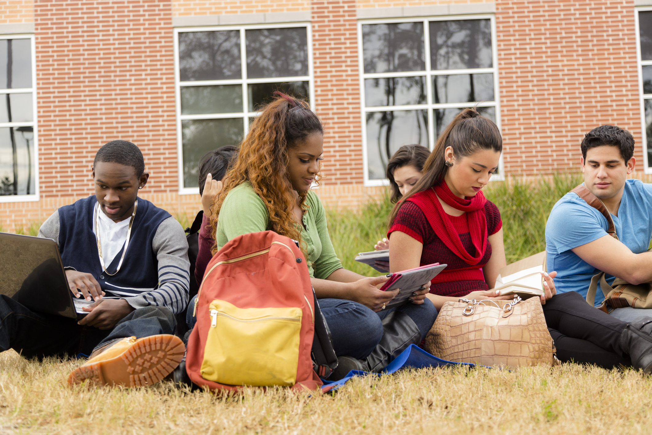Multi-ethnic group of college student friends. Digital tablet, laptop.