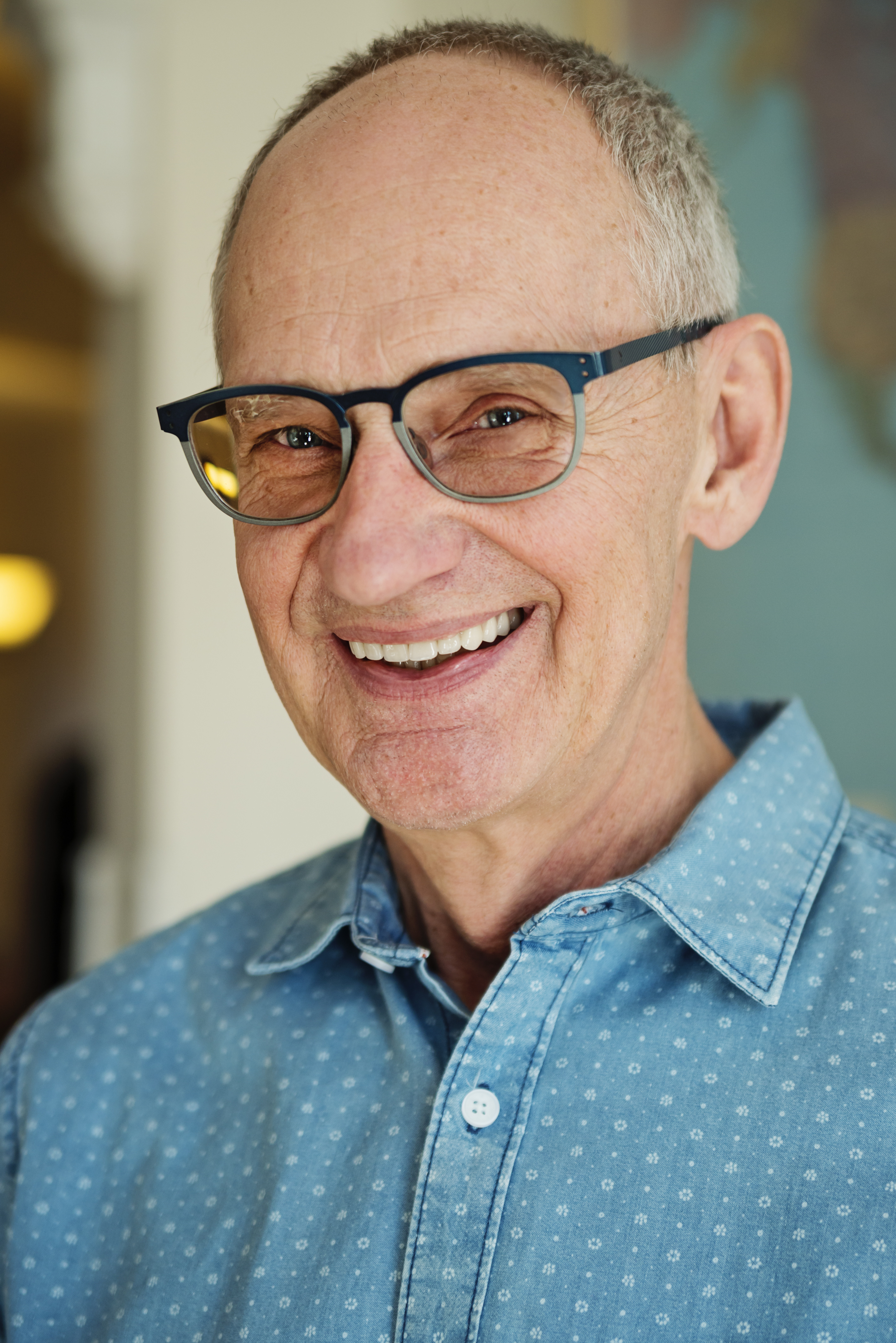 Portrait of bald senior man with glasses smiling.