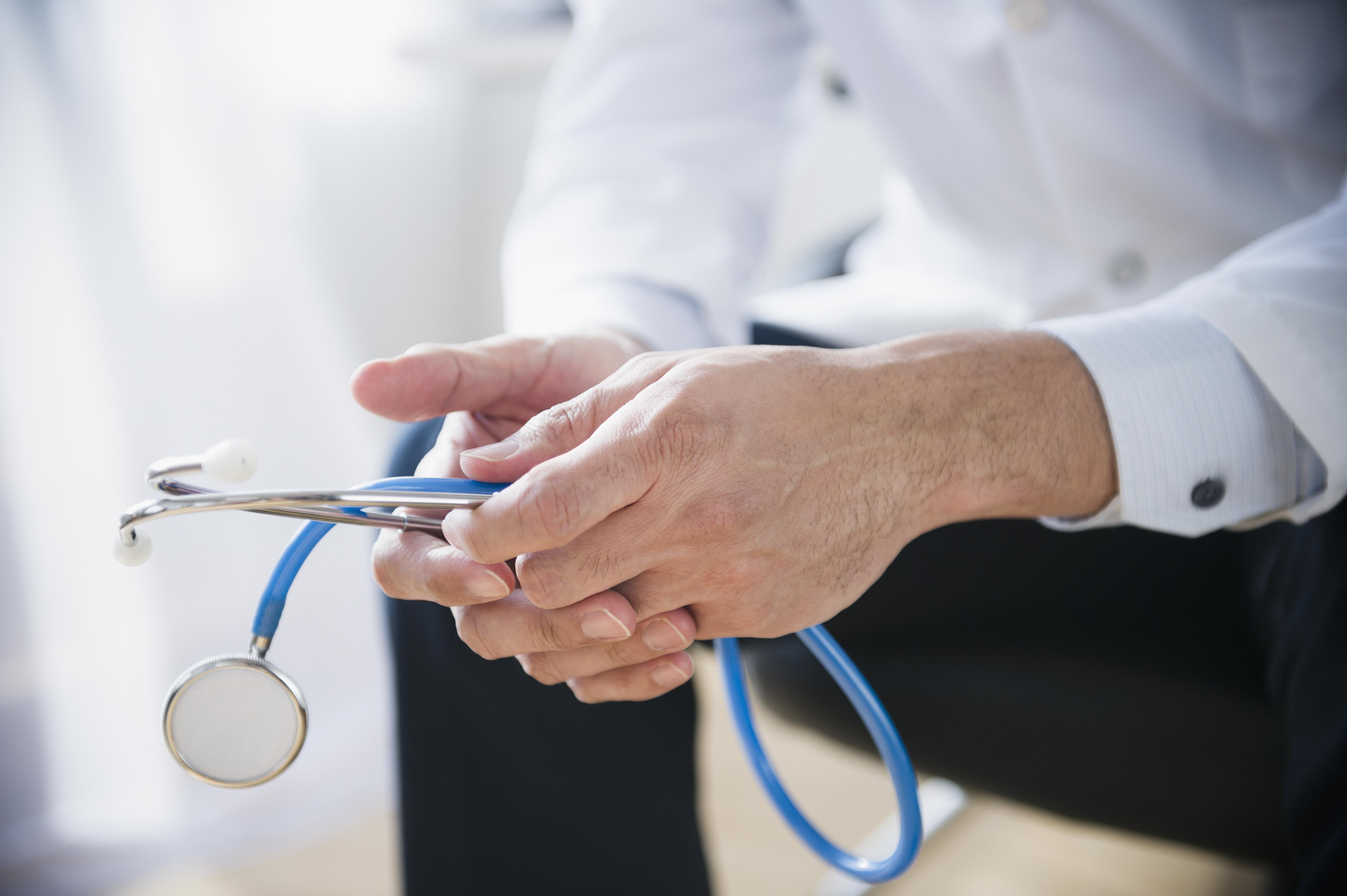 Mixed race doctor's hands holding stethoscope