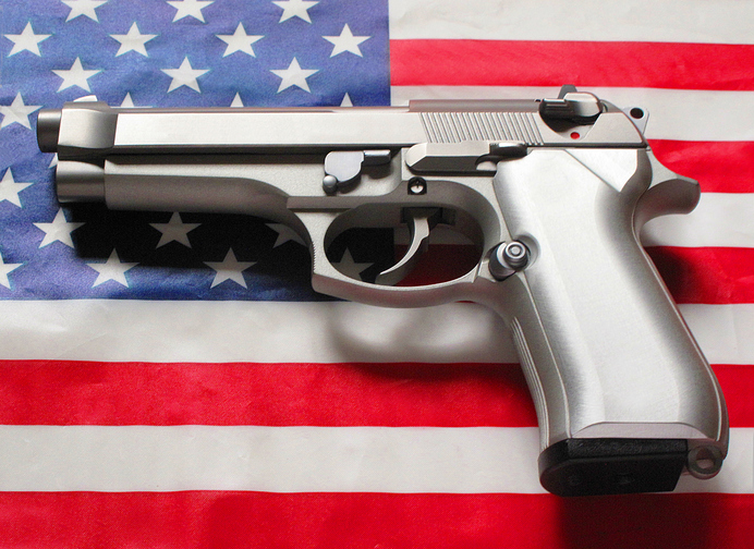 Stainless steel 9 mm caliber handgun laying on an American flag background - part of a series