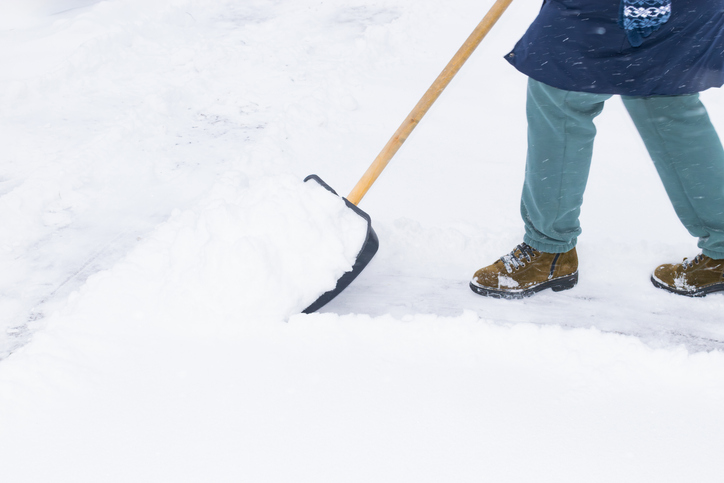 an unrecognizable man cleans snow with a shovel in a snowfall