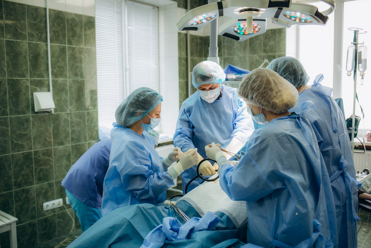 surgeons perfoming surgery operation of abdominal cesarean section during child delivery birth at clinic operating room.