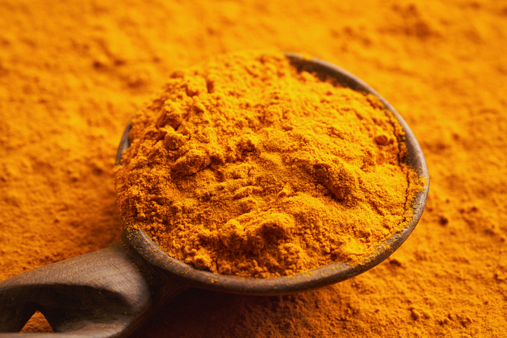 Ground turmeric root powder on a wooden spoon