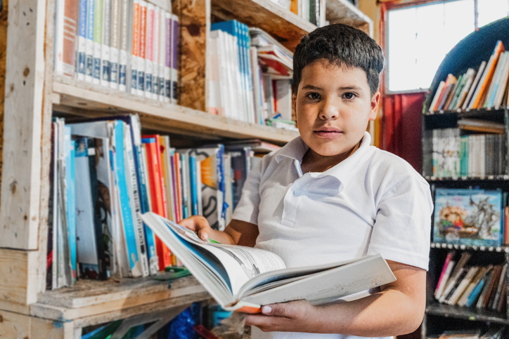 Portrait of a boy holding a book in the library