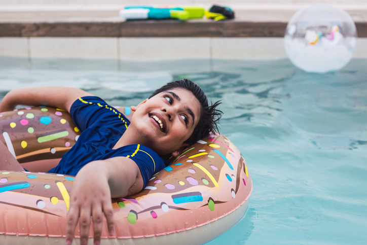 Boy in swimming pool with inflatable donut on summer vacation