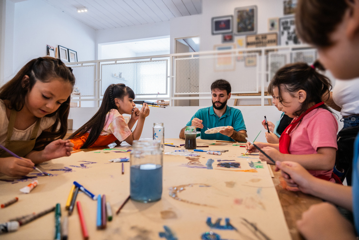 Kids painting on cardboard poster during paint class at workshop